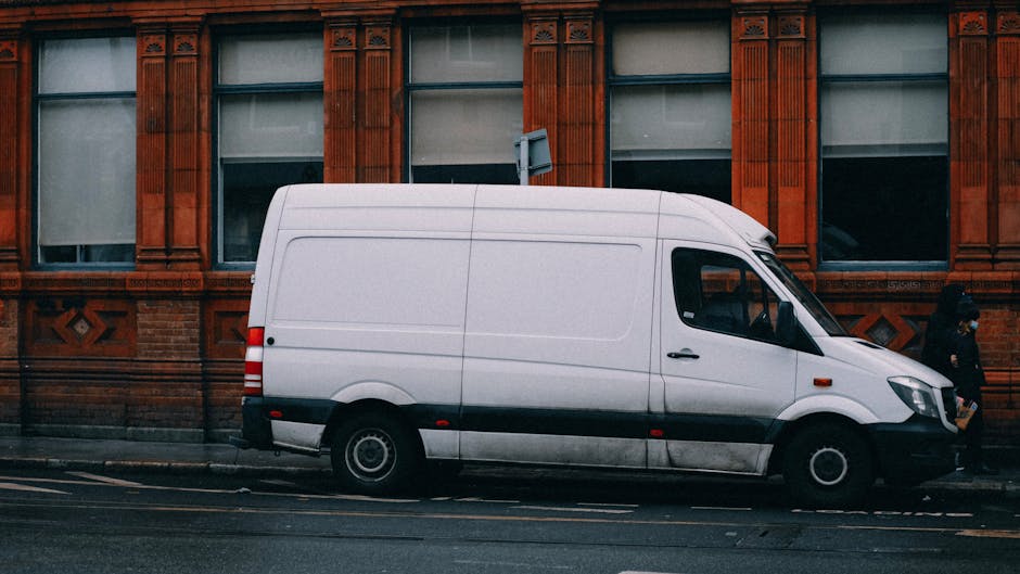 The back of a large moving van with its rear doors open, revealing an interior packed with various sized cardboard boxes, some labeled fragility, stacked on top of each other with packing paper and pl