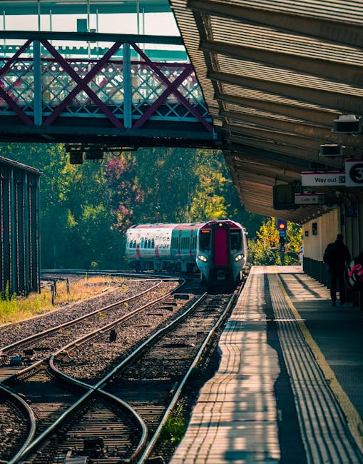 A view of multiple modern passenger trains parked on railway tracks in a train station, with some trains facing forward and others partially visible from the side; the trains are primarily white with